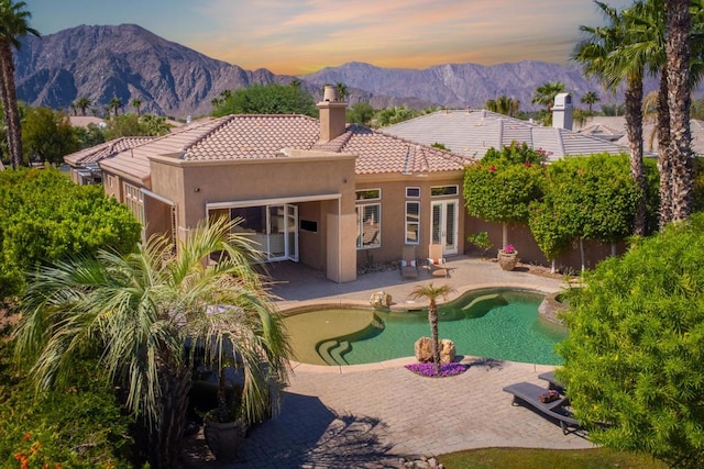 pool at dusk with a mountain view and a patio