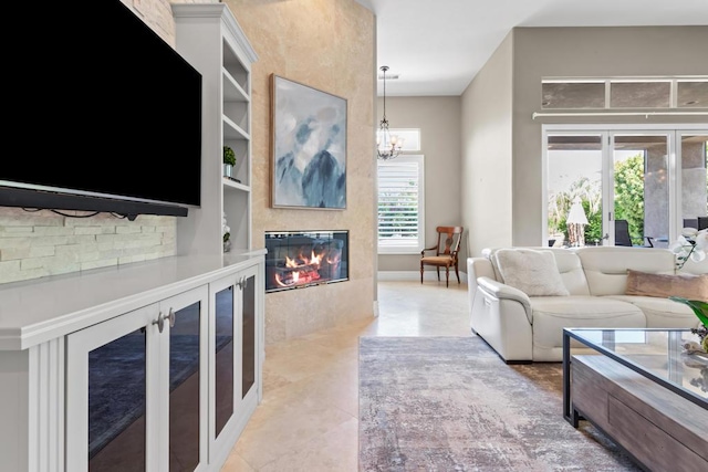 living room featuring an inviting chandelier, a large fireplace, and built in features