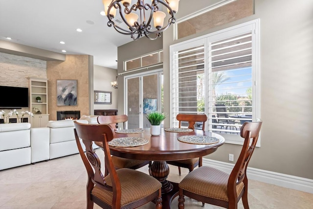 dining area featuring a notable chandelier, built in shelves, and a large fireplace