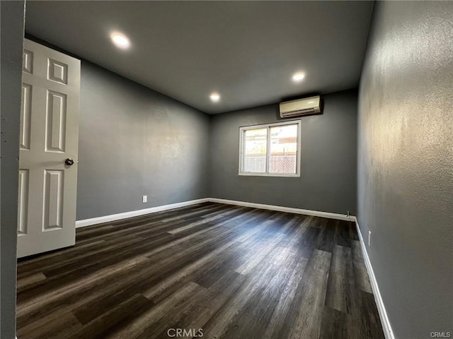 spare room featuring dark hardwood / wood-style floors and an AC wall unit