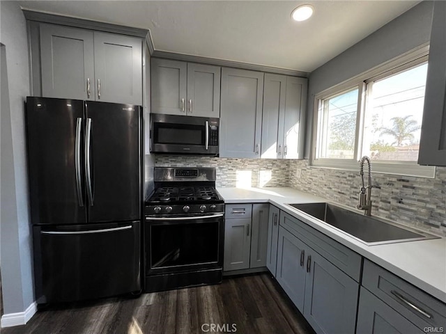 kitchen featuring gray cabinetry, sink, black gas stove, and refrigerator