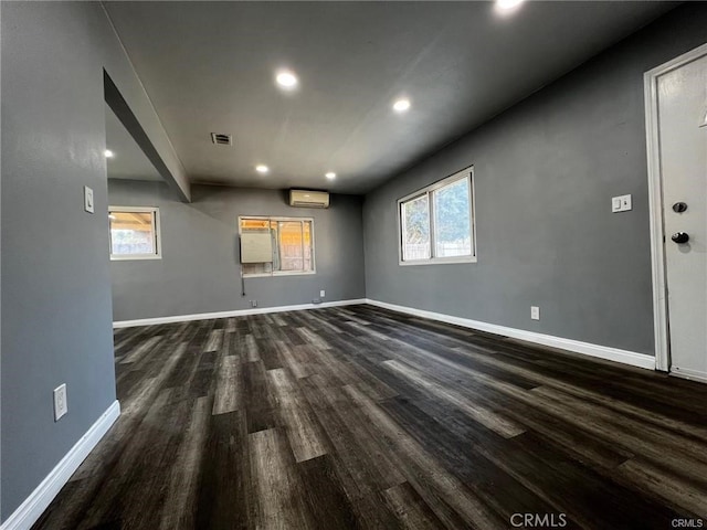 empty room with a wall mounted air conditioner and dark hardwood / wood-style floors