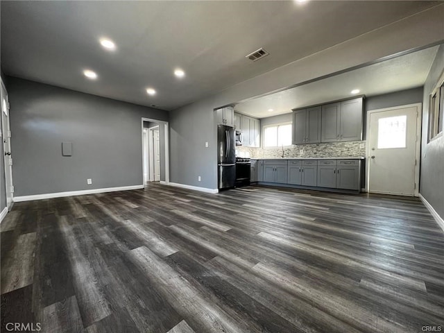 interior space featuring tasteful backsplash, appliances with stainless steel finishes, dark hardwood / wood-style flooring, and gray cabinets