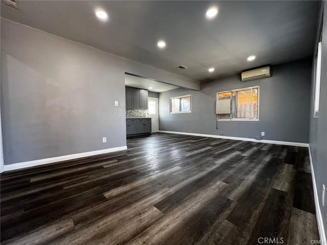 unfurnished living room with dark hardwood / wood-style floors and an AC wall unit