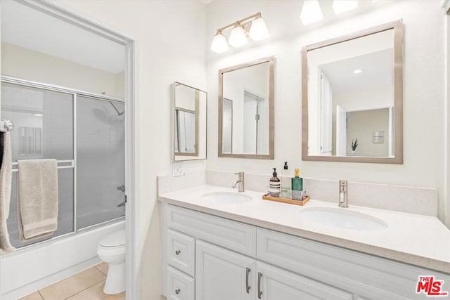 full bathroom with bath / shower combo with glass door, toilet, vanity, and tile patterned flooring