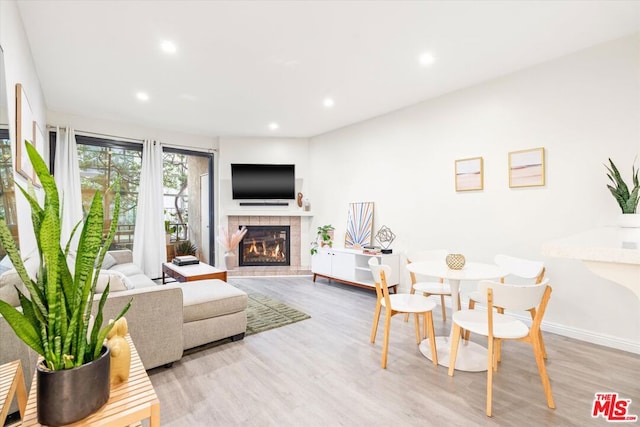 living room with a tile fireplace and light hardwood / wood-style floors