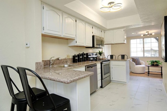 kitchen featuring a breakfast bar area, kitchen peninsula, white cabinets, and appliances with stainless steel finishes