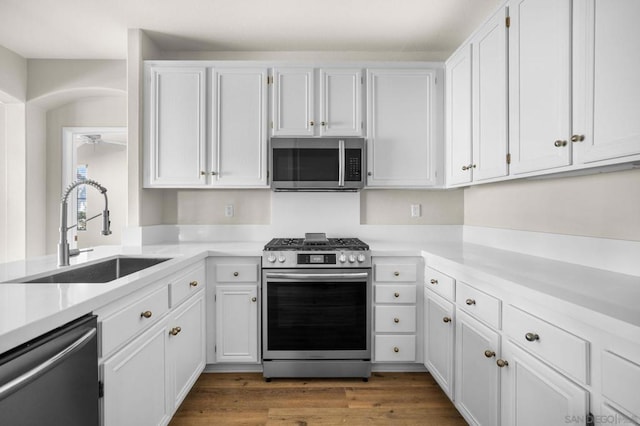 kitchen with white cabinets, appliances with stainless steel finishes, sink, and dark hardwood / wood-style flooring