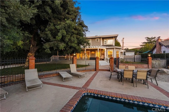 patio terrace at dusk with a fenced in pool and a pergola