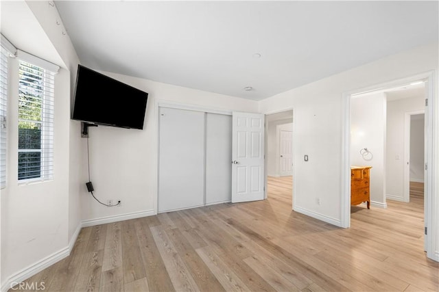 unfurnished bedroom featuring light wood-type flooring and a closet