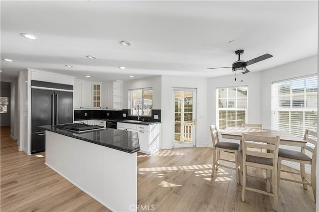 kitchen with decorative backsplash, light hardwood / wood-style flooring, white cabinets, and black appliances