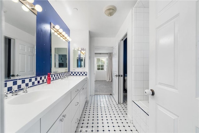 bathroom with a tub to relax in, vanity, and backsplash