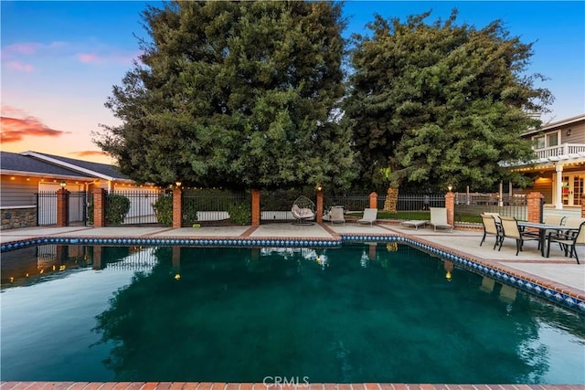 pool at dusk featuring a patio