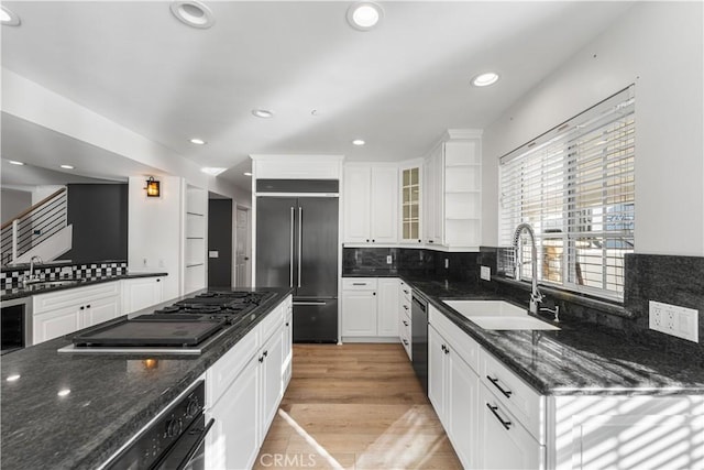 kitchen featuring dishwashing machine, sink, white cabinetry, dark stone countertops, and built in fridge