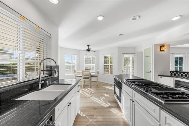 kitchen featuring white cabinets, black oven, sink, and stainless steel gas stovetop