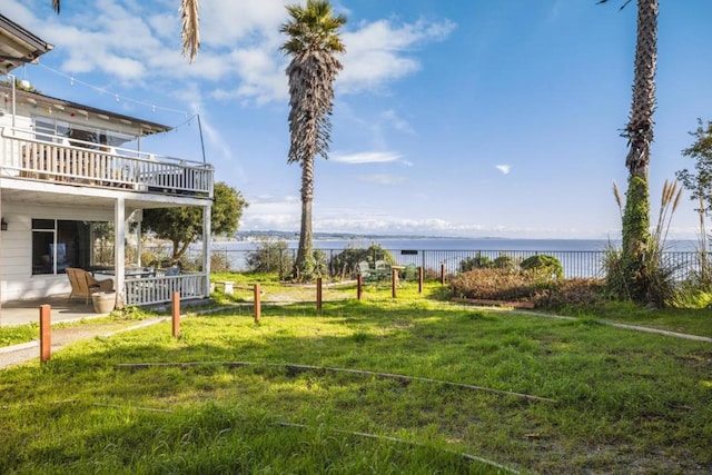 view of yard featuring a patio area, a balcony, and a water view