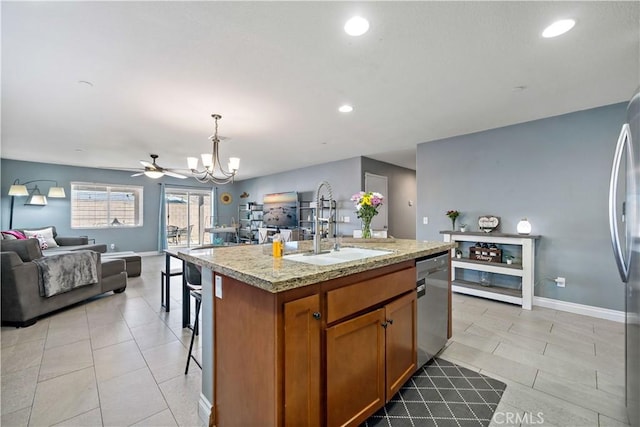 kitchen with sink, decorative light fixtures, light tile patterned floors, stainless steel dishwasher, and a kitchen island with sink