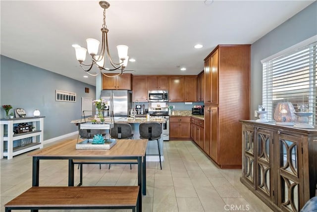 kitchen with pendant lighting, a kitchen island with sink, light stone counters, stainless steel appliances, and an inviting chandelier