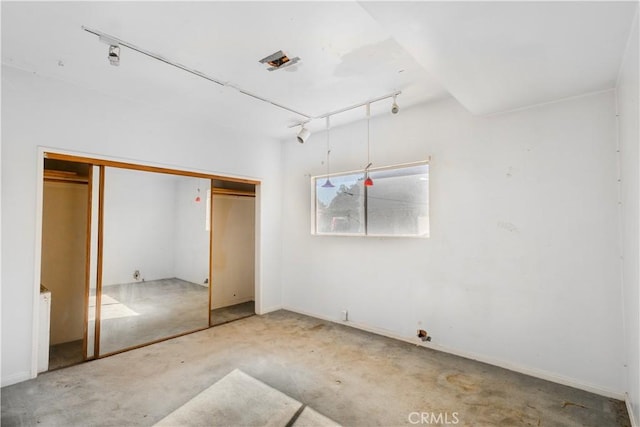 unfurnished bedroom with track lighting and a closet