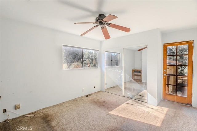 unfurnished bedroom featuring light colored carpet, ceiling fan, and a closet