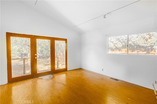 spare room featuring lofted ceiling and hardwood / wood-style flooring