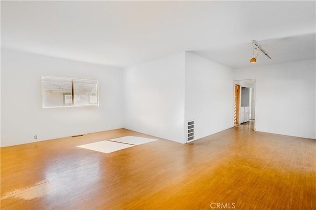 spare room featuring hardwood / wood-style flooring and track lighting