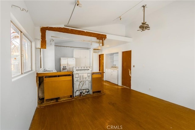 kitchen featuring vaulted ceiling, hardwood / wood-style floors, washing machine and clothes dryer, and stainless steel fridge with ice dispenser