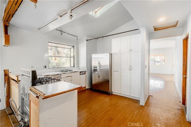 kitchen with stainless steel refrigerator with ice dispenser, white cabinetry, rail lighting, and light hardwood / wood-style flooring