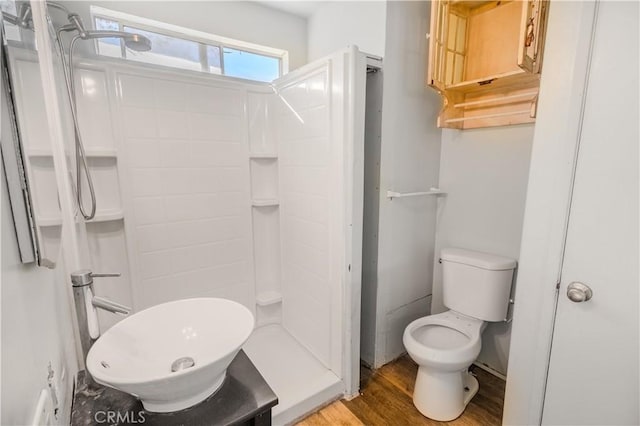 bathroom with hardwood / wood-style flooring, a shower, and toilet