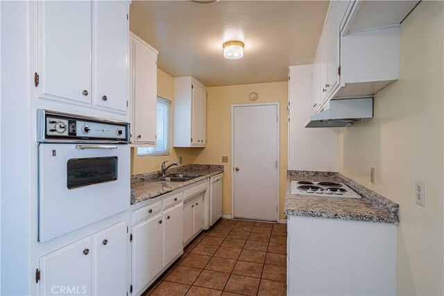 kitchen with dark tile patterned flooring, sink, white appliances, and white cabinets