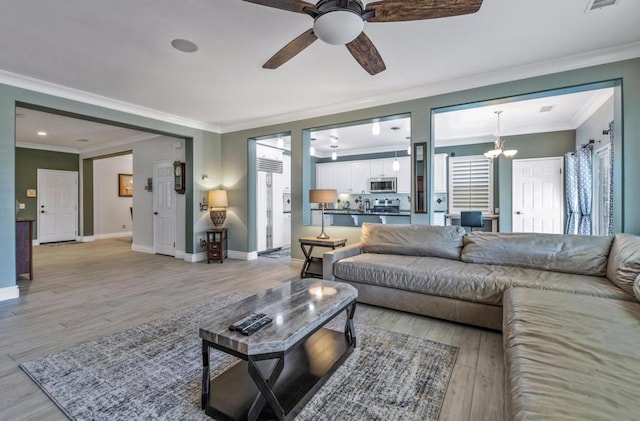 living room featuring ceiling fan with notable chandelier, crown molding, and light hardwood / wood-style flooring