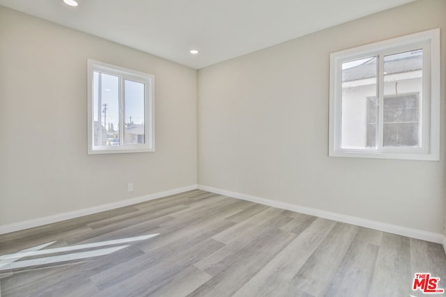 empty room with plenty of natural light and light hardwood / wood-style flooring