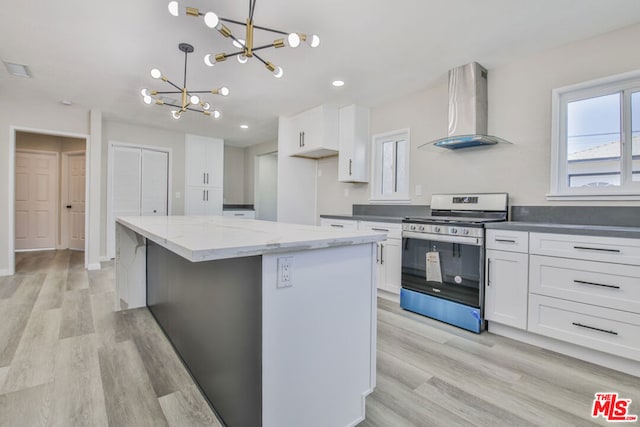 kitchen featuring stainless steel range, white cabinetry, wall chimney exhaust hood, and pendant lighting