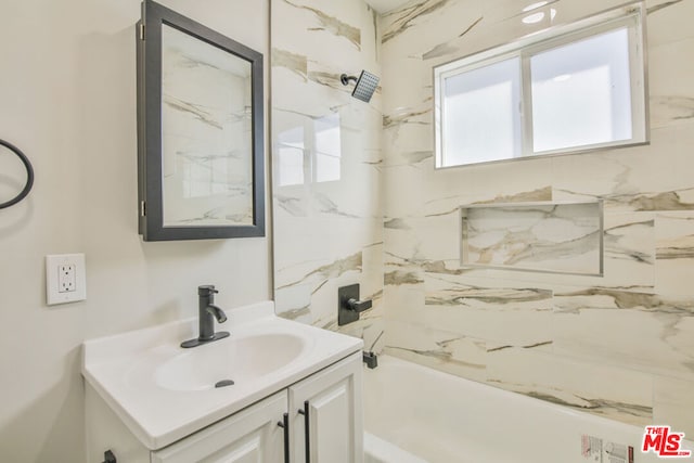 bathroom with tiled shower / bath combo and vanity