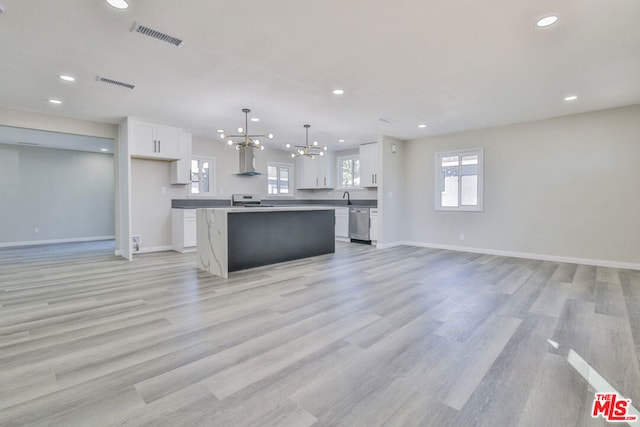 kitchen with white cabinetry, a notable chandelier, hanging light fixtures, a kitchen island, and light hardwood / wood-style flooring