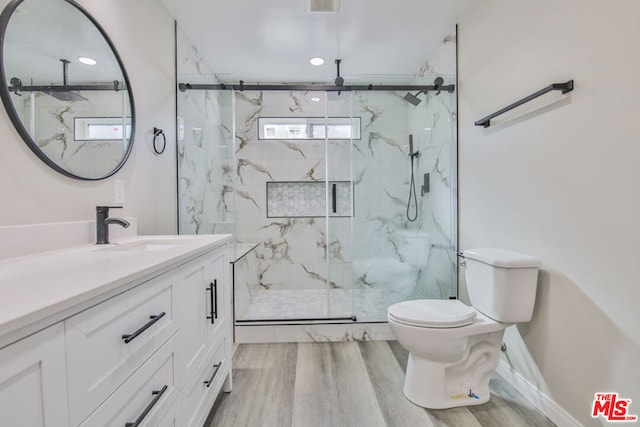 bathroom with toilet, wood-type flooring, vanity, and an enclosed shower