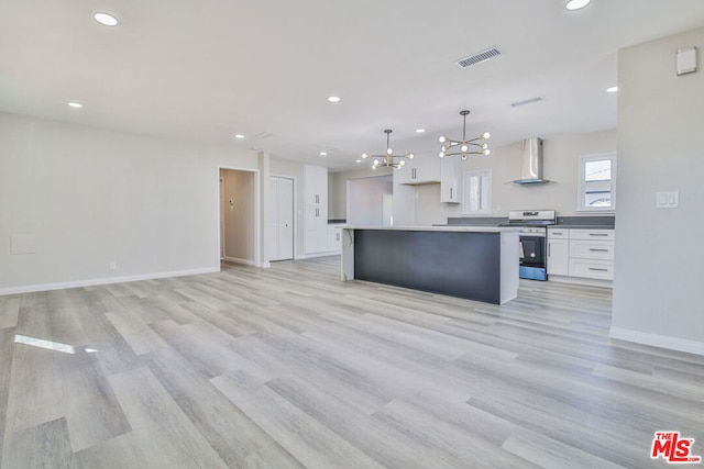 kitchen with a notable chandelier, wall chimney range hood, pendant lighting, stainless steel range with electric stovetop, and white cabinets