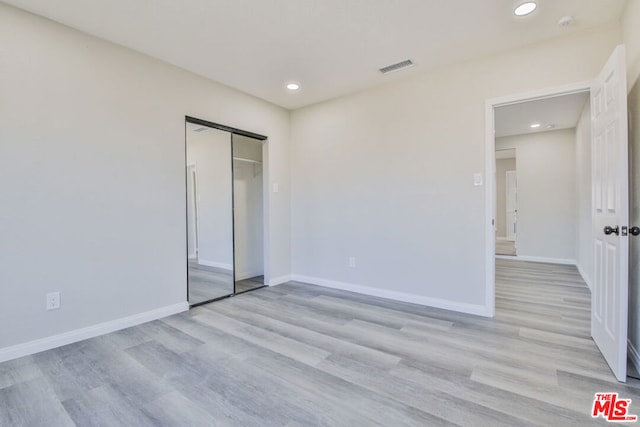 unfurnished bedroom with light hardwood / wood-style floors and a closet