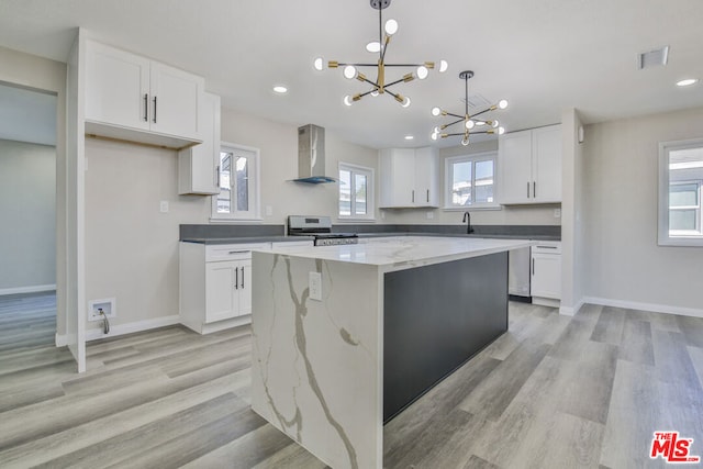 kitchen featuring wall chimney range hood, white cabinets, stainless steel electric range oven, and a kitchen island