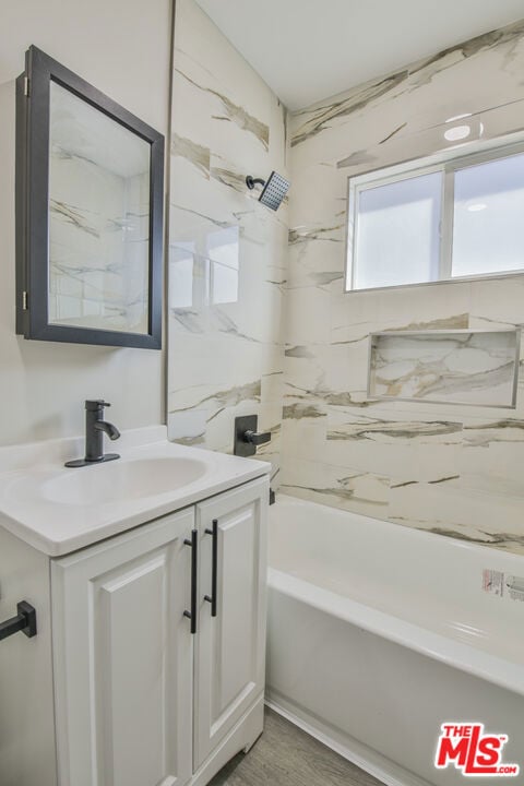 bathroom with hardwood / wood-style flooring, vanity, and shower / washtub combination