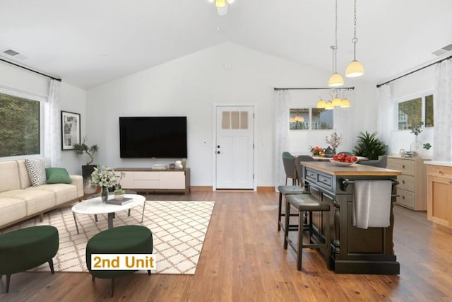 living room featuring vaulted ceiling, ceiling fan, a wealth of natural light, and light hardwood / wood-style floors