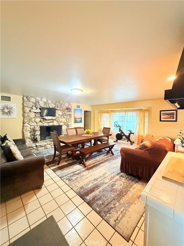 tiled living room featuring a stone fireplace