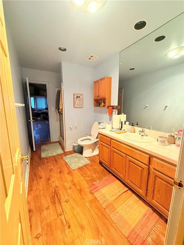 bathroom featuring toilet, vanity, and hardwood / wood-style floors