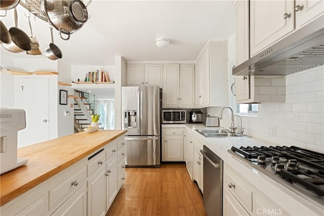 kitchen with white cabinets, appliances with stainless steel finishes, decorative backsplash, sink, and butcher block countertops