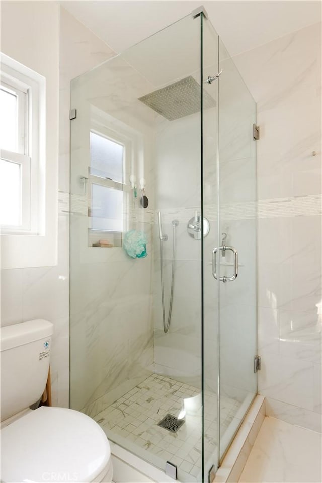 bathroom with an enclosed shower, tile walls, and toilet