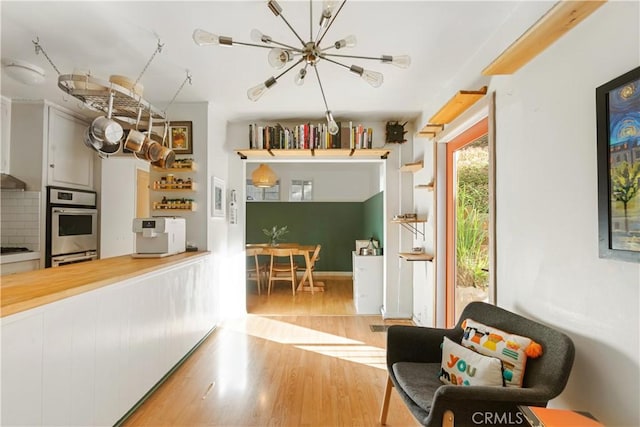 kitchen featuring light hardwood / wood-style floors, gas stovetop, double oven, and an inviting chandelier