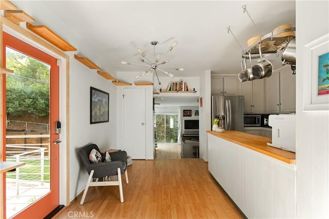 kitchen with appliances with stainless steel finishes, wooden counters, gray cabinetry, and light hardwood / wood-style flooring