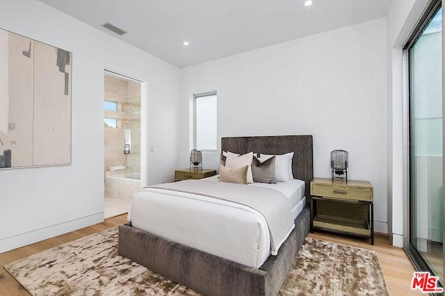 bedroom featuring connected bathroom and light wood-type flooring