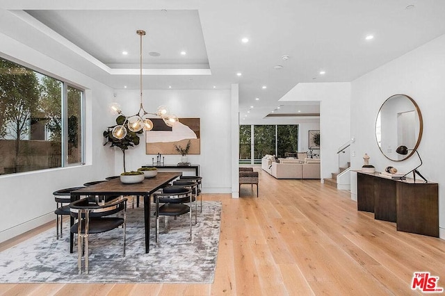 dining space featuring light hardwood / wood-style floors, plenty of natural light, a tray ceiling, and a chandelier