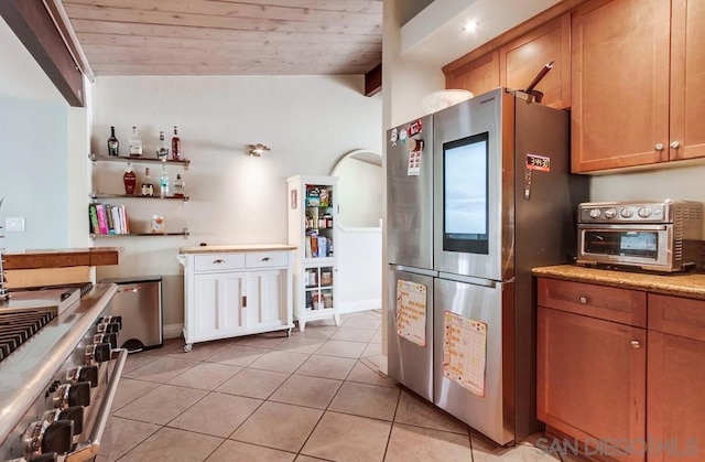 kitchen with vaulted ceiling, appliances with stainless steel finishes, light tile patterned floors, light stone counters, and wooden ceiling